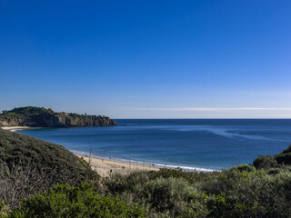 Coastline with beach and sea from a hillside under a clear blue sky