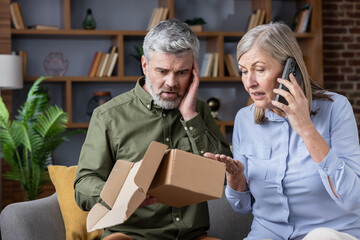 Mature couple feeling shocked and disappointed, discovering an empty delivery package upon opening it at home, with the woman calling to complain about the fraud