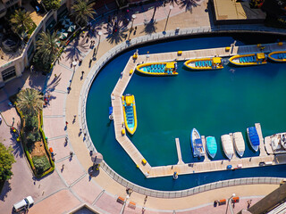 Aerial drone view of Dubai Marina harbor with many luxury yachts, capturing modern waterfront and city skyline. Floating boats on canal
