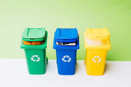 Colorful recycling bins arranged in a row against a vibrant green background, promoting eco-friendly waste management and sustainability practices
