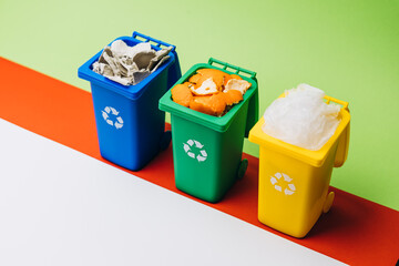 Colorful recycling bins filled with various waste materials, positioned on a vibrant background, promoting environmental awareness and sustainability practices