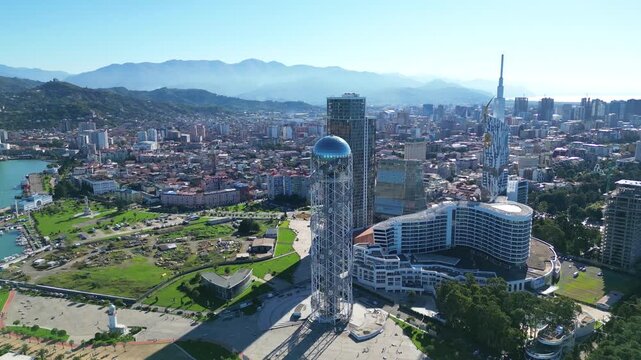 Bird's-eye view of Batumi landmarks in clear winter. 4K horizontal drone footage captures the city's architecture, iconic buildings, and streets under sunny skies during a warm snowless winter.