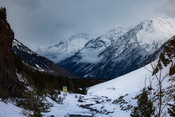 Snowy Mountain Valley with River, Forest and Cloudy Sky