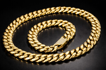 A cuban gold bracelet and necklace on black background