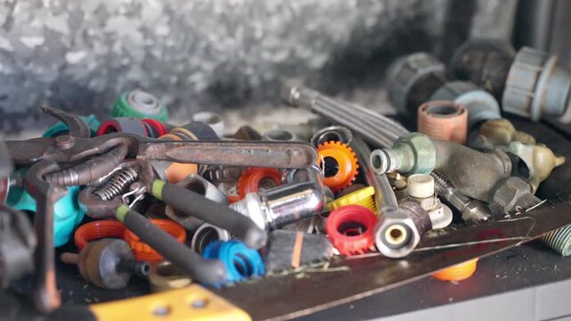 Assorted hand tools mechanical parts and hardware on workshop table