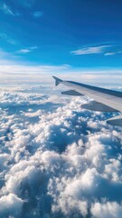 Obraz premium View from an airplane window: wing extending into a blue sky above fluffy white clouds. Concept Airplane window view, Wing against blue sky, Fluffy white clouds, Aerial travel photography