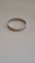 Clean shot of a simple metallic wedding band or fashion ring with a smooth polished finish on a light background