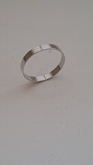 Clean shot of a simple metallic wedding band or fashion ring with a smooth polished finish on a light background
