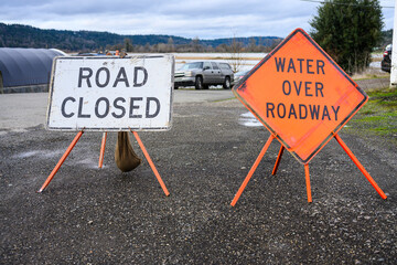 Signs in flooding of Road Closed and orange diamond Water Over Roadway