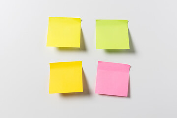Fototapeta premium four blank colorful sticky notes on white wall. Template mock up