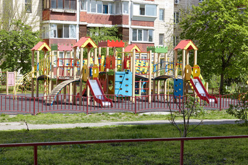 Colorful playground on yard with no children in Kyiv, Ukraine. Play yard with slide, and other playground elements. Urban neighborhood childhood concept