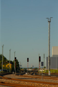 rail tracks converging at signal crossing under open sky, multiple signals and poles lining corridor, industrial rails leading toward horizon, calm lighting and clear perspective