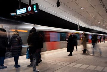 Commuters waiting on metro platform with motion blur. Rush hour metro station