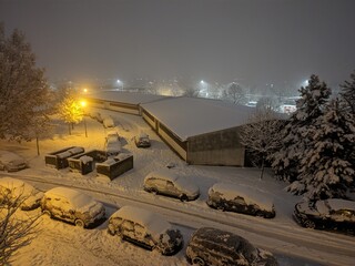 Winter night in the city with snow-covered cars, sidewalks and roads. Snow disaster in a housing estate in Eastern Europe.