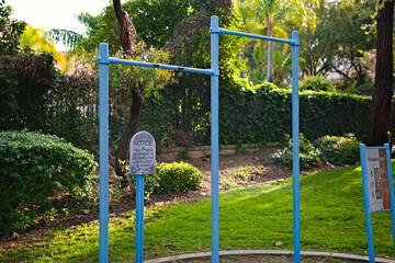 Outdoor fitness pull up bars and exercise station in a public park surrounded by greenery in...