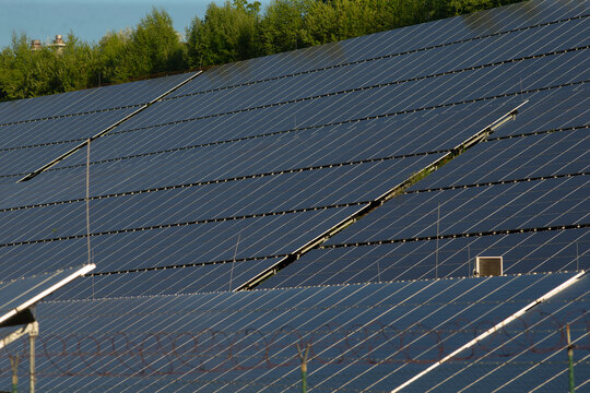 Closeup photovoltaic panels showing rails and reflection, detailed hardware view with connectors, glass surfaces, and mounting frames, technical atmosphere highlighting engineering