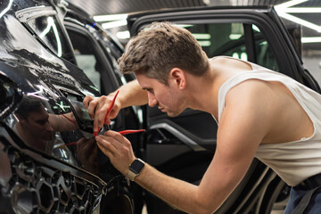 A car wrapping specialist applies a polyurethane film to the car. Detailer smoothes PPF. Car...