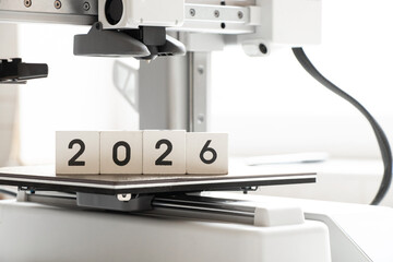Desktop 3D printer on a white background and the year 2026 on cubes. Modern technologies of...