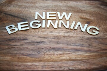 New beginning message created from wooden letters on wood material background with copy space representing fresh starts, motivation and life change concepts.