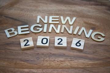 Fototapeta premium New beginning 2026 message created from wooden letters on wood material background with copy space representing fresh starts, motivation and life change concepts.