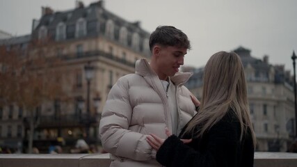 A young couple embraces in Paris France with classic Parisian architecture visible in the background The scene captures a moment of love and affection between the man and woman in an urban setting.