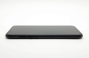 Side view of a black smartphone with a blank dark screen on a white background. The device has buttons on its side. This offers ample copy space for custom text or graphics, suitable for advertising.