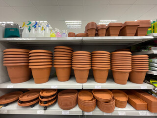Shelves with stacked terracotta flower pots, trays and planters in a garden store. Gardening...