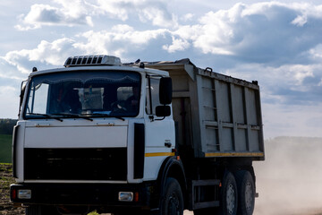 Blue sky with cumulus clouds, truck driving on dirt road