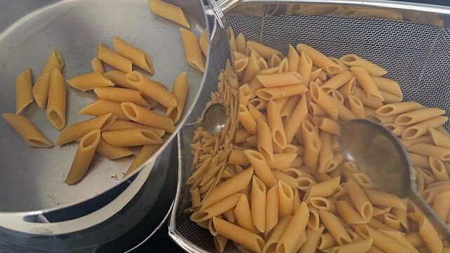 Transferring cooked penne pasta pot.