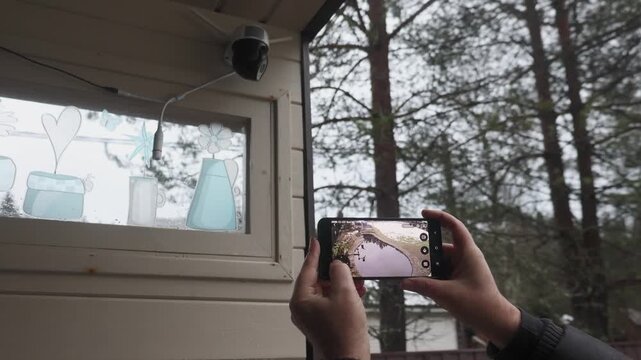 Hands holding hold smartphone that controls outdoor security camera. control home using smart home mobile app. High quality 4k footage