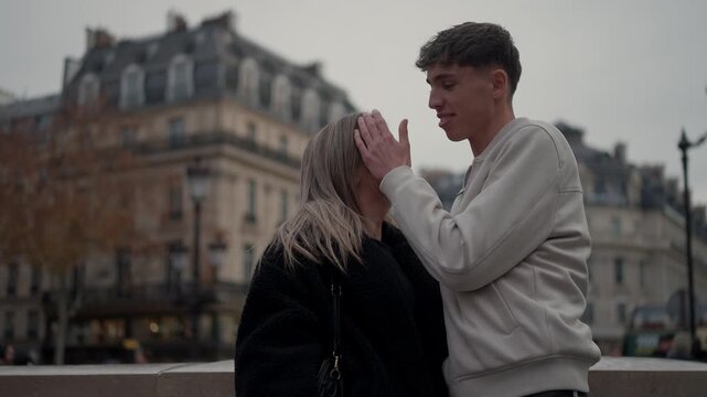A romantic couple embraces in Paris France with Parisian architecture in the background The young man and woman share a loving moment in the city on an overcast.