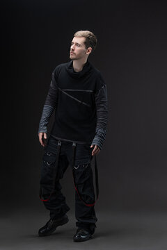 Street style: young man in baggy cyberpunk fashion posing on studio gray