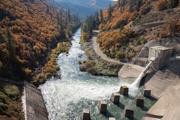 Pit River flowing downstream from Pit 3 Dam in autumn, surrounded by vibrant fall foliage and rugged canyon landscape in Shasta County, California.