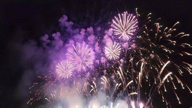 Vibrant fireworks exploding in the night sky with purple and gold colors