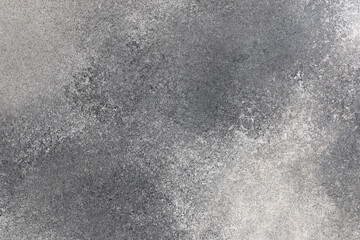 Gray textured surface showing variation in shades and patterns from scattered particles