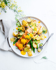 Top-down view of a plated salmon fillet with roasted potatoes and green vegetables, presented as a fresh and healthy gourmet meal.
