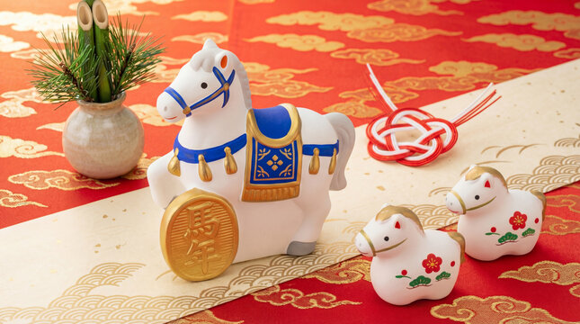 Japanese New Year decoration for Year of the Horse with white zodiac figurines, pine ornament and mizuhiki on red fabric