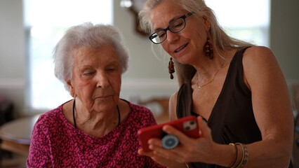 An elderly woman and her daughter enjoy time sharing memories and connecting through video calls on a smartphone at home