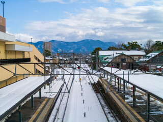 冬空が背景の線路や屋根に積雪がある冬景色の長浜駅から見える景色