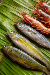 Fototapeta premium A close-up of freshly caught seafood (generic fish, prawns) laid out on a banana leaf, ready for traditional cooking.