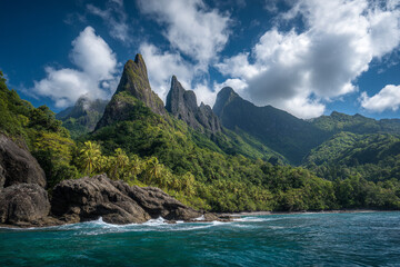 The dramatic, lush peaks of the Finschhafen Coast, showing dense rainforest meeting turquoise ocean under a vast sky.