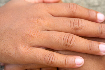Fototapeta premium A stack of children's hands on a cement background as a symbol of teamwork and friendship.