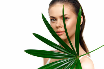 Portrait of a young woman holding a green palm leaf, showcasing natural beauty and serenity, ideal for wellness and eco-friendly themes.
