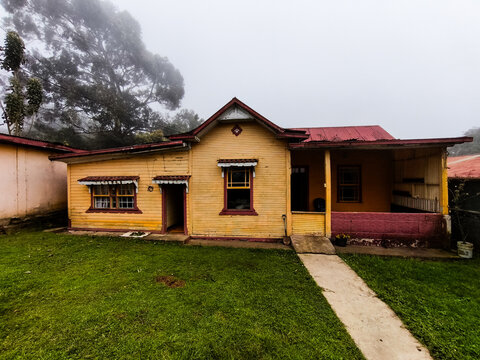 Traditional Yellow Wooden House in Foggy Rural Landscape