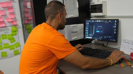 Worker at computer managing customer orders and logistics in modern office environment