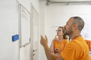 Two electrical company employees discussing upcoming maintenance tasks while reviewing data on a computer