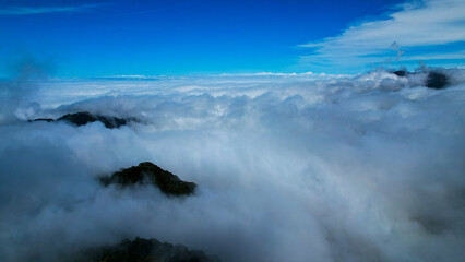 Obraz premium Aerial View of Mountains Rising Above a Sea of Clouds
