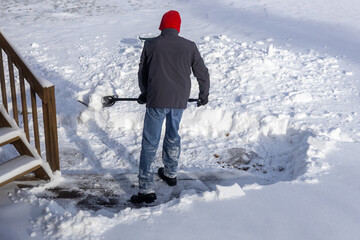 Back side of an unrecognizable adult shoveling deep snow following a blizzard