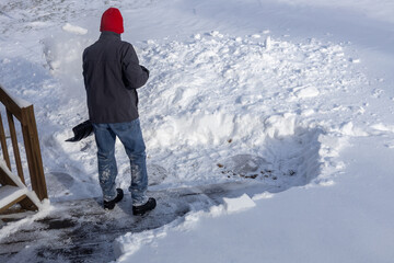 Back side of an unrecognizable adult shoveling deep snow following a blizzard