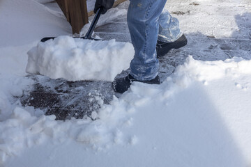 Partial view of an unrecognizable adult shoveling deep snow following a blizzard